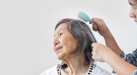 elderly woman combing hair by caregiverの写真素材