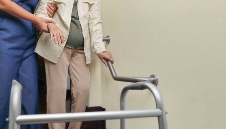 Elderly woman holding on handrail with caregiverの写真素材