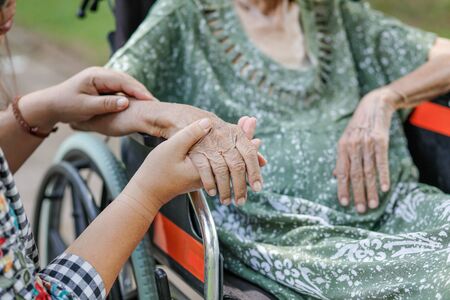 Elderly asian woman on wheelchair at home with daughter take careの写真素材