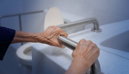 Elderly woman holding on handrail in bathroomの写真素材