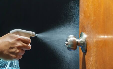 Cleaning door knob with alcohol spray for  Covid-19 (Coronavirus) prevention.の写真素材