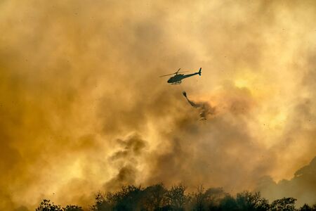 Helicopter dumping water on forest fireの写真素材