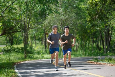 Father and adult son jogging on the park pathの写真素材