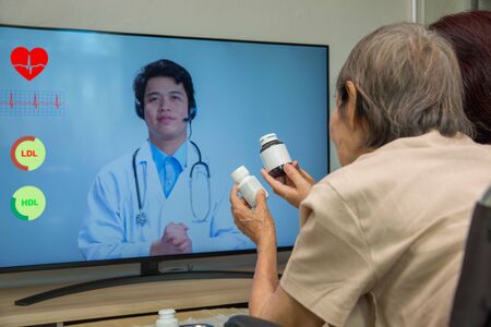 Elderly woman sit at home having online consultation with doctor on tablet computer.の写真素材
