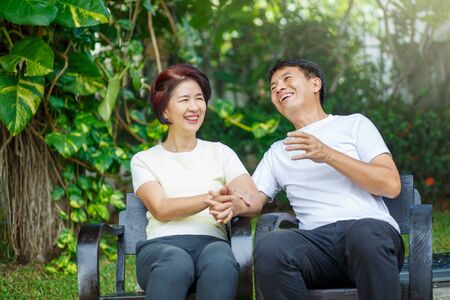 Middle aged couple relax sitting on bench in backyard.の写真素材