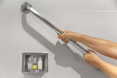 Senior woman holding on handrail for safety in bathroomの写真素材