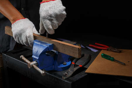 Closeup workers hands on a  wooden plank locked in the iron viseの写真素材