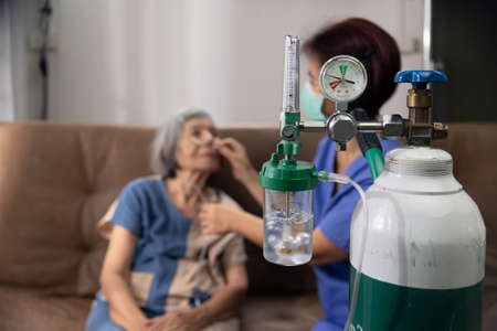 Elderly woman wearing oxygen nasal canula at home.の写真素材