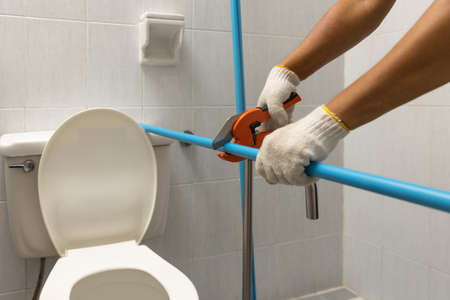 Worker installing floating pipeline on the wall in the old bathroomの写真素材