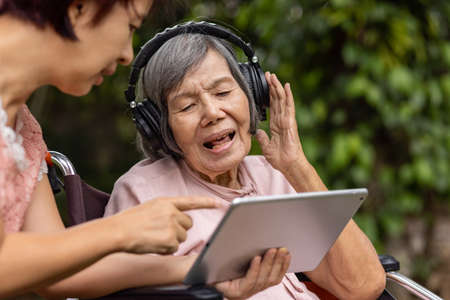 senior woman and daughter listening music with headphone in backyardの写真素材