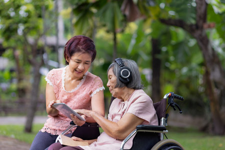 senior woman and daughter listening music with headphone in backyardの写真素材