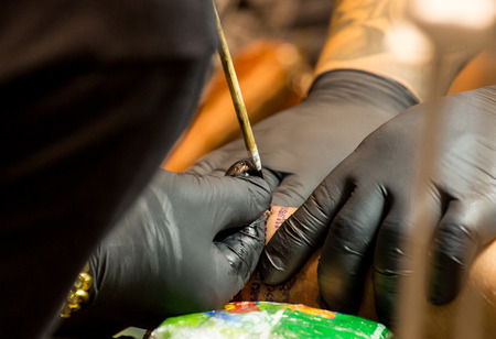 Professional tattoo artist makes a tattoo on a man's back.の写真素材