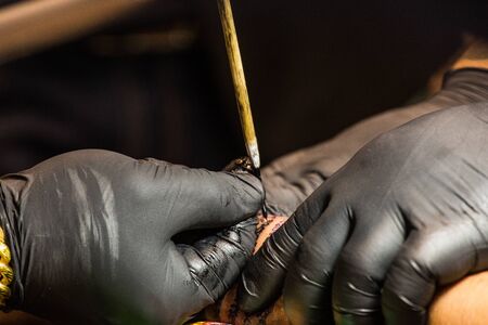 Professional tattoo artist makes a tattoo on a man's back.の写真素材