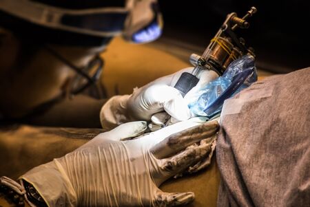 Professional tattoo artist makes a tattoo on a man's back with an electronic tattoo machine.の写真素材