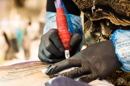Professional tattoo artist makes a tattoo on a man's backの写真素材