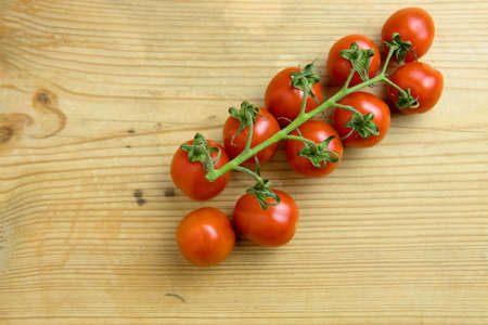 Lot of whole fresh red coctail tomato flatlay on an rustic  wooden tableの写真素材