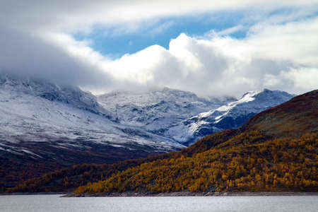Autumn in the high mountain with colorful hill and a snow cowered mountain in the distance.の写真素材