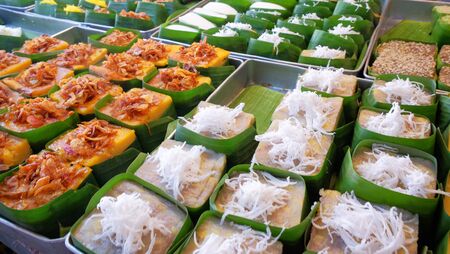 Banana rice cake and Pumpkin coconut custard cake in banana leaf packaging on tray Thai traditional dessert sweet at shop.の写真素材