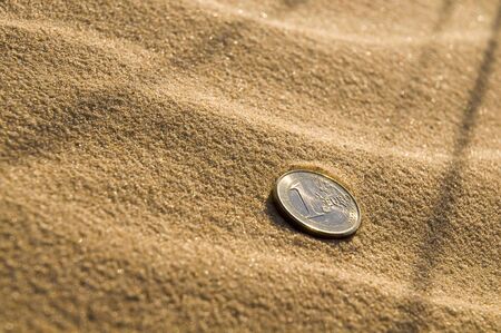 Euro coin lying in sand on the beach の写真素材