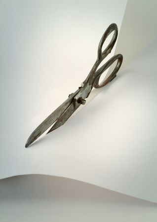 Old scissors cutting a sheet of paperの写真素材