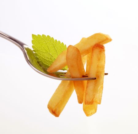 French fries on a fork against white backgroundの写真素材