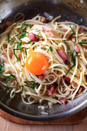 Spaghetti with bacon, onion and egg on a frying pan の写真素材