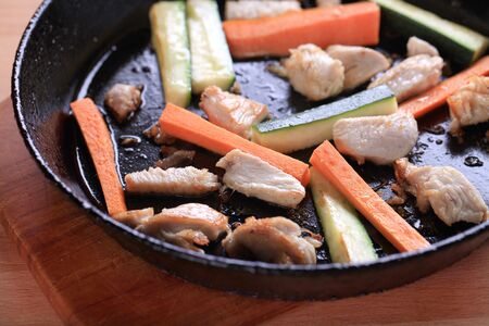 Chicken meat and vegetables on a frying panの写真素材
