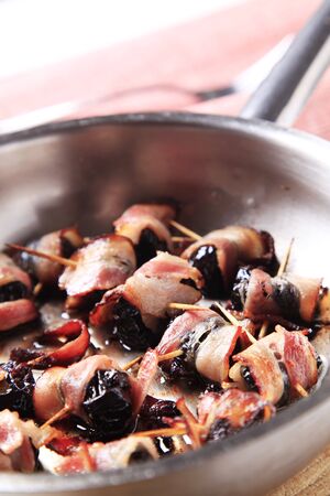 Bacon wrapped prunes in a saucepanの写真素材
