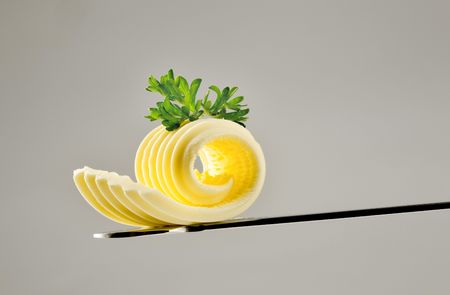 Butter curl on a knife topped with parsleyの写真素材