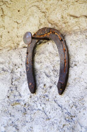 Rusty horseshoe hanging on a nail on a wallの写真素材
