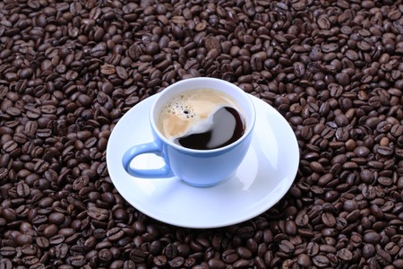 Cup of black coffee on a bed of coffee beansの写真素材
