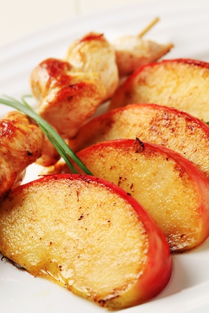 Chicken skewer and slices of baked apple の写真素材