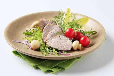 Roast pork tenderloin served with vegetables and mushroomsの写真素材