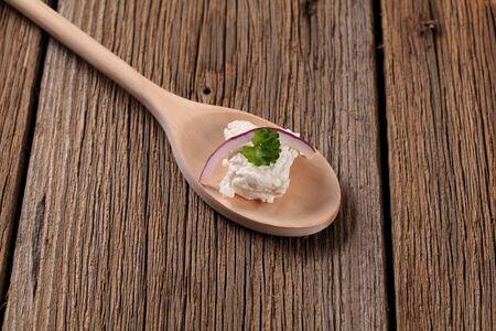 Fresh cheese on a wooden spoon - closeupの写真素材