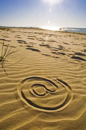 At sign drawn in the sand on the beachの写真素材