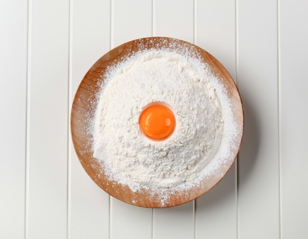 Fresh egg yolk and heap of flourの写真素材