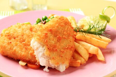 Fried fish served with French fries and mixed vegetablesの写真素材