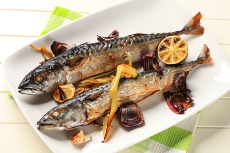Two baked mackerel and vegetables on a platterの写真素材