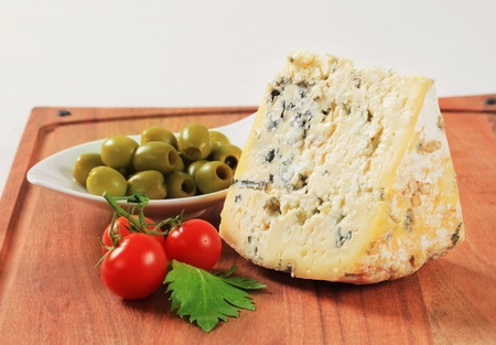Wedge of blue cheese and bowl of olives on cutting boardの写真素材