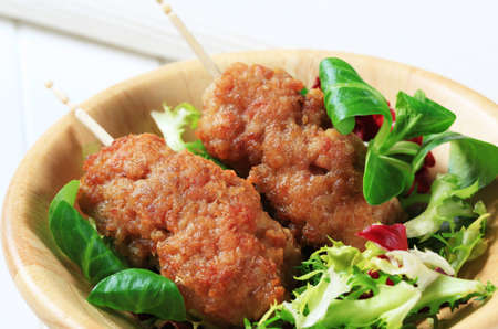 Rolled minced meat on stick and fresh salad