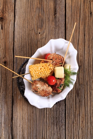 Minced meat kebabs on wooden skewers and roasted sweetcornの写真素材