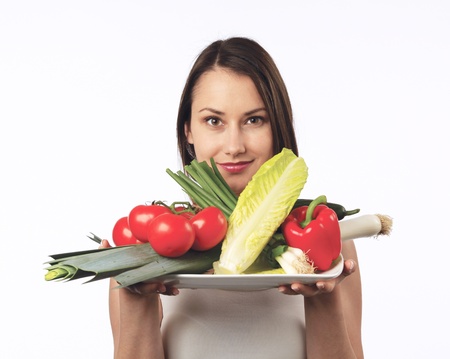 Young woman holding a plate with fresh vegetablesの写真素材