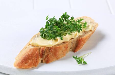 Slice of baguette with butter and cressの写真素材
