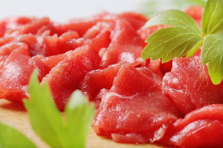 Thinly sliced raw beef meat on cutting boardの写真素材