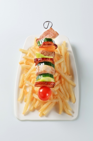 Pork and vegeable skewer with French friesの写真素材