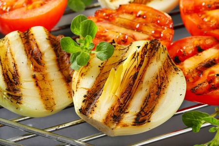 Grilled tomatoes and onions on barbecue gridの写真素材