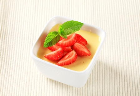 Small dish of vanilla pudding topped with strawberriesの写真素材