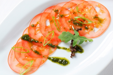 Thinly sliced tomato with pesto and spring onionの写真素材