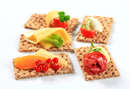 Whole grain crisp bread slices with various toppingsの写真素材