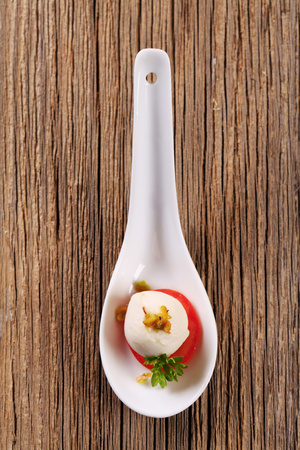 Baby mozzarella and tomato on porcelain spoonの写真素材